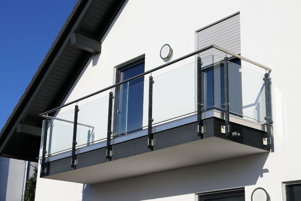 Moderner Stahlbalkon mit Glasgeländer an weißer Fassade – Beispiel für individuell geplante Metallbauelemente und Metall-Geländer in Kobenz